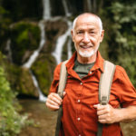 Portrait of a Senior hiker standing next to the mountain creek